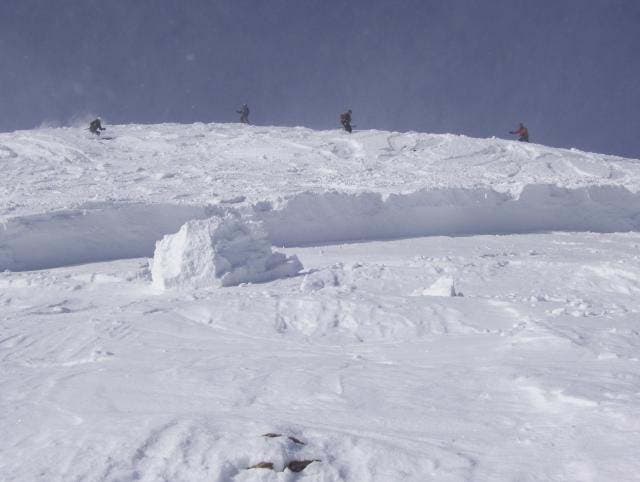 A view of the crown as skiers descend to begin a beacon search.  The portion of snow remaining is called hangfire.  It poses its own avalanche risk…
