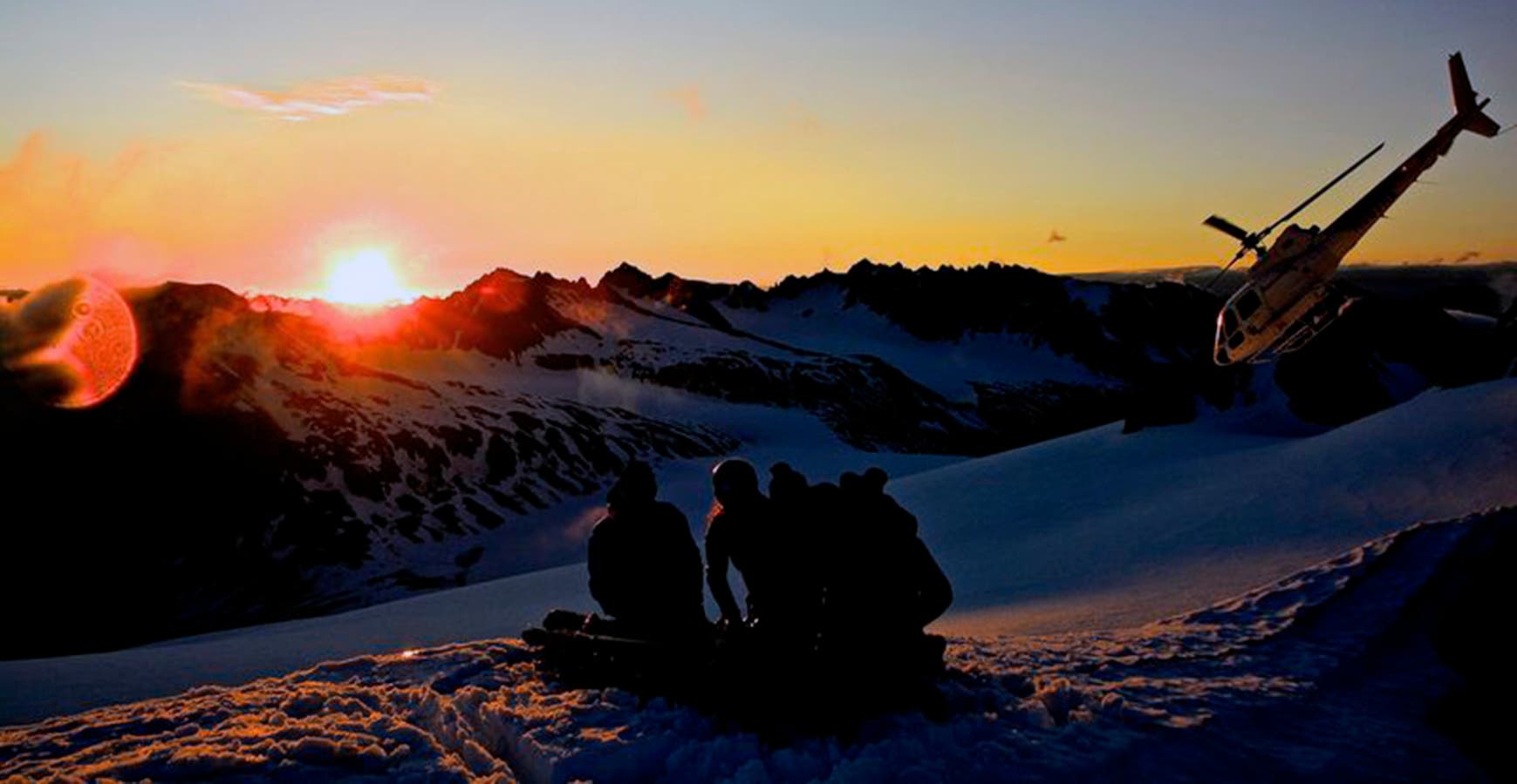 A Tordrillo Mountain Lodge group watches the heli and sun disappear in Alaska.