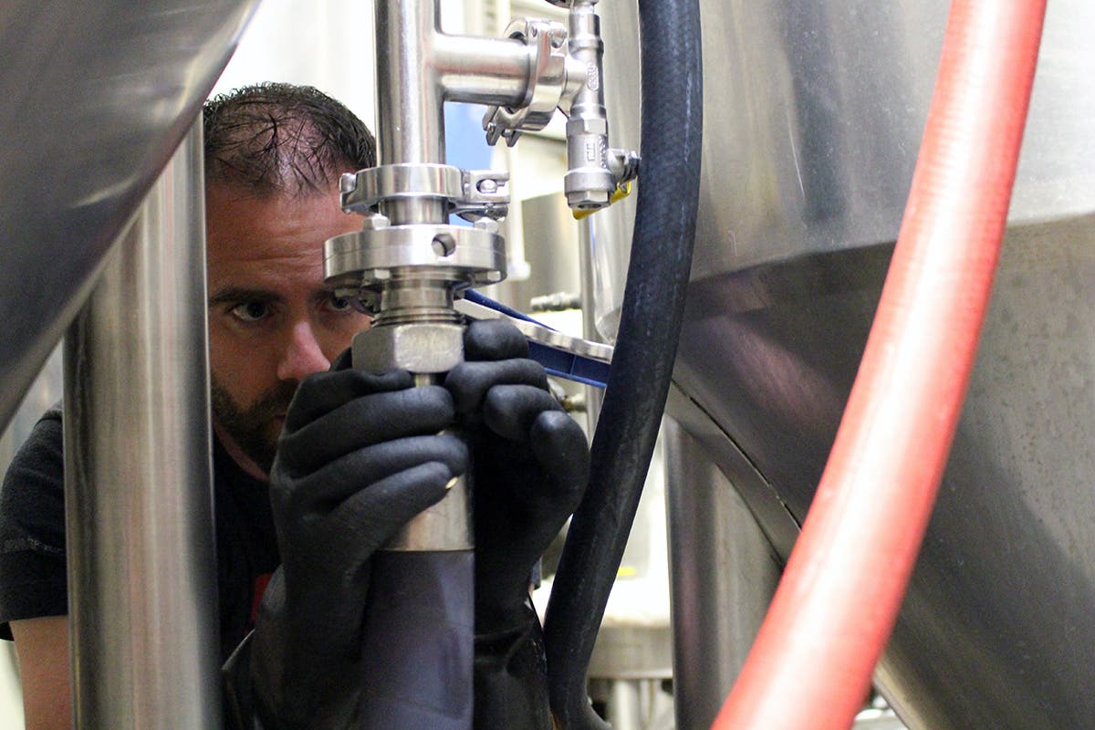 Hooked Up Ryan Dionne hooks up lines to start the transfer of hot water into the brew tank.