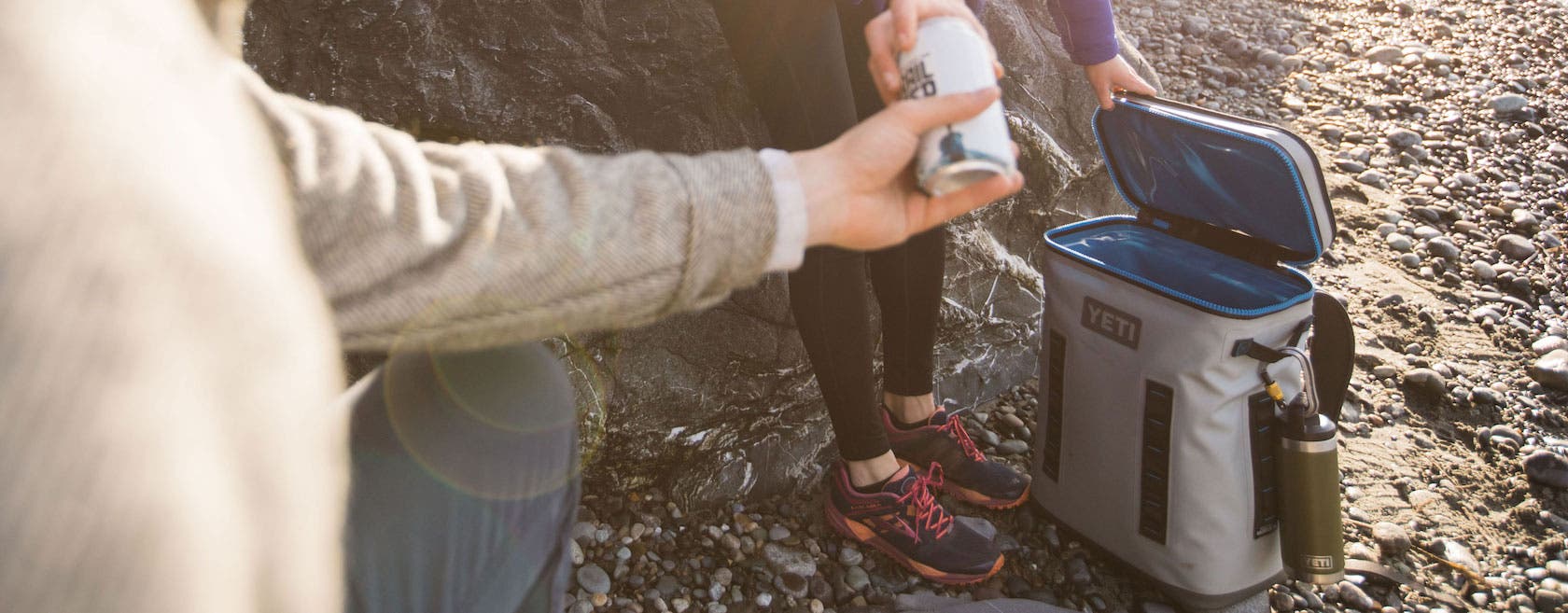 Someone handing off a drink from their Yeti hopper backflip
