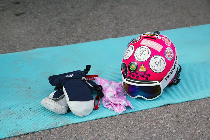 Softgoods Pink sticker-covered helmet, pink and gray gaiter, and gray and black gloves on top of a blue yoga mat.