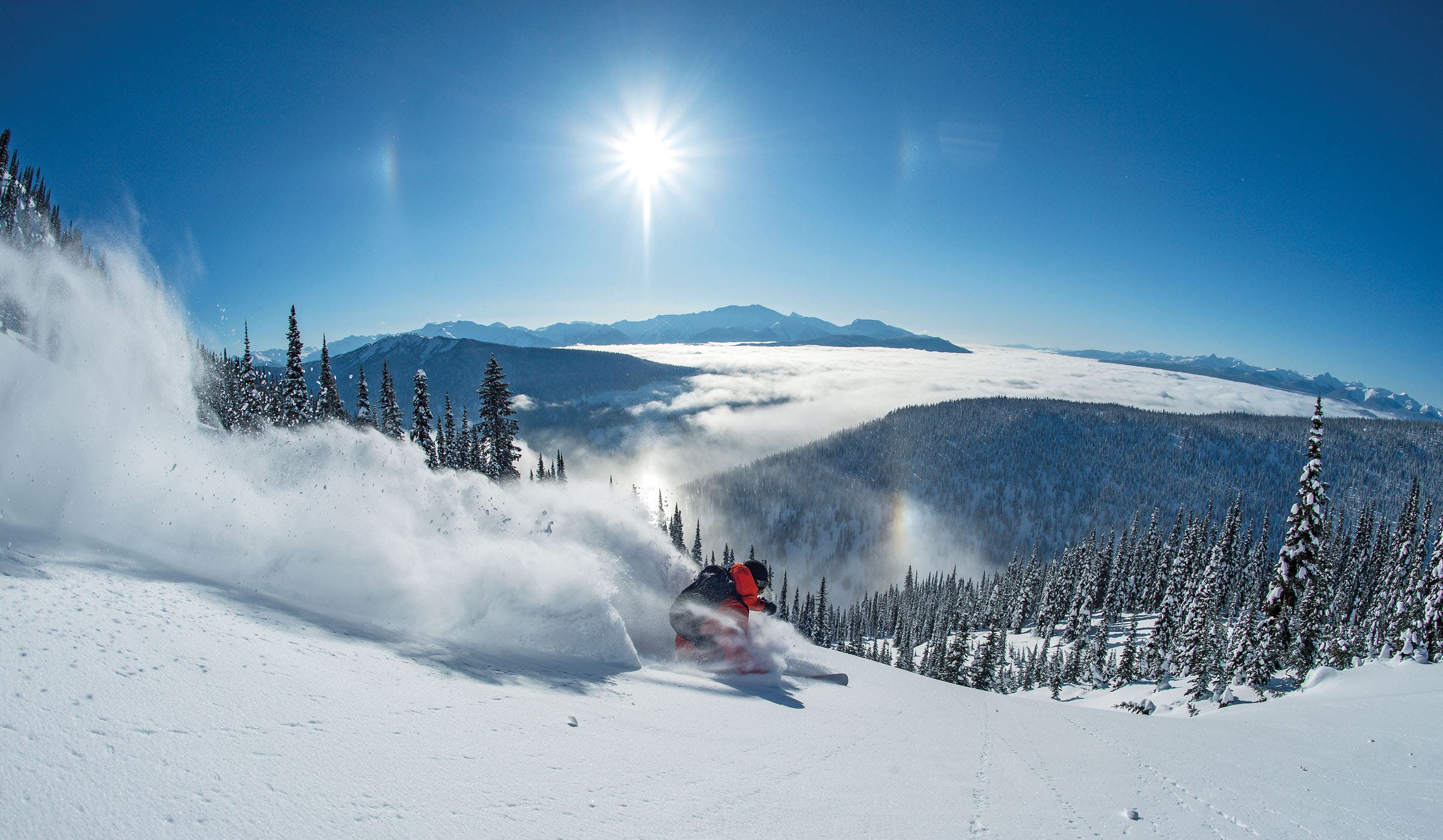 Skier in red ski jacket skiing at Silver Tip Lodge and Heli-skiing in British Columbia, Canada.