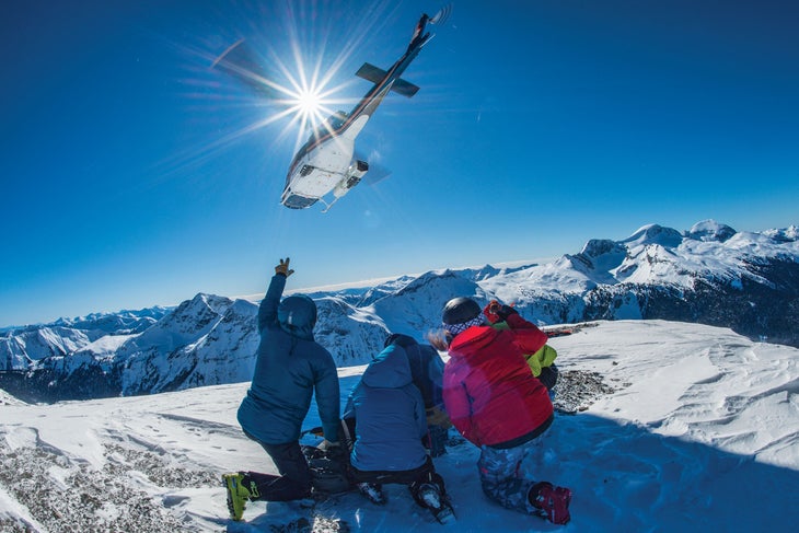 SKI1119-UTL4_SilvertipHeli_ByEricBerger_1 copy Helicopter flying over a group of three heli-skiers at Silvertip Lodge and Heli-skiing in the Cariboo Mountains