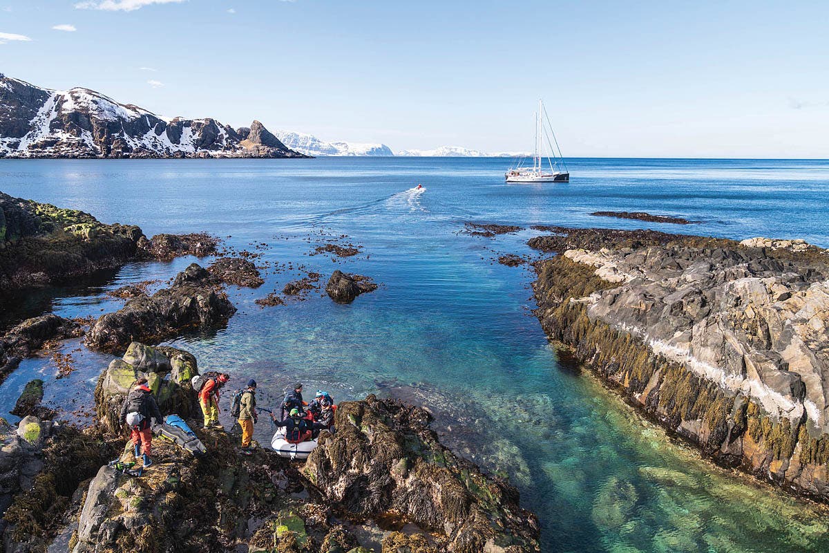 A crew of skiers return to their sailboat in Norway.