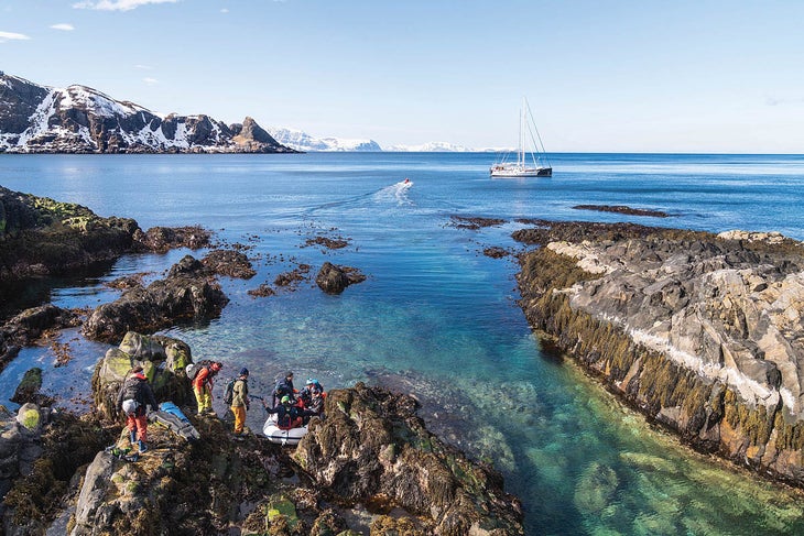 A crew of skiers return to their sailboat in Norway.