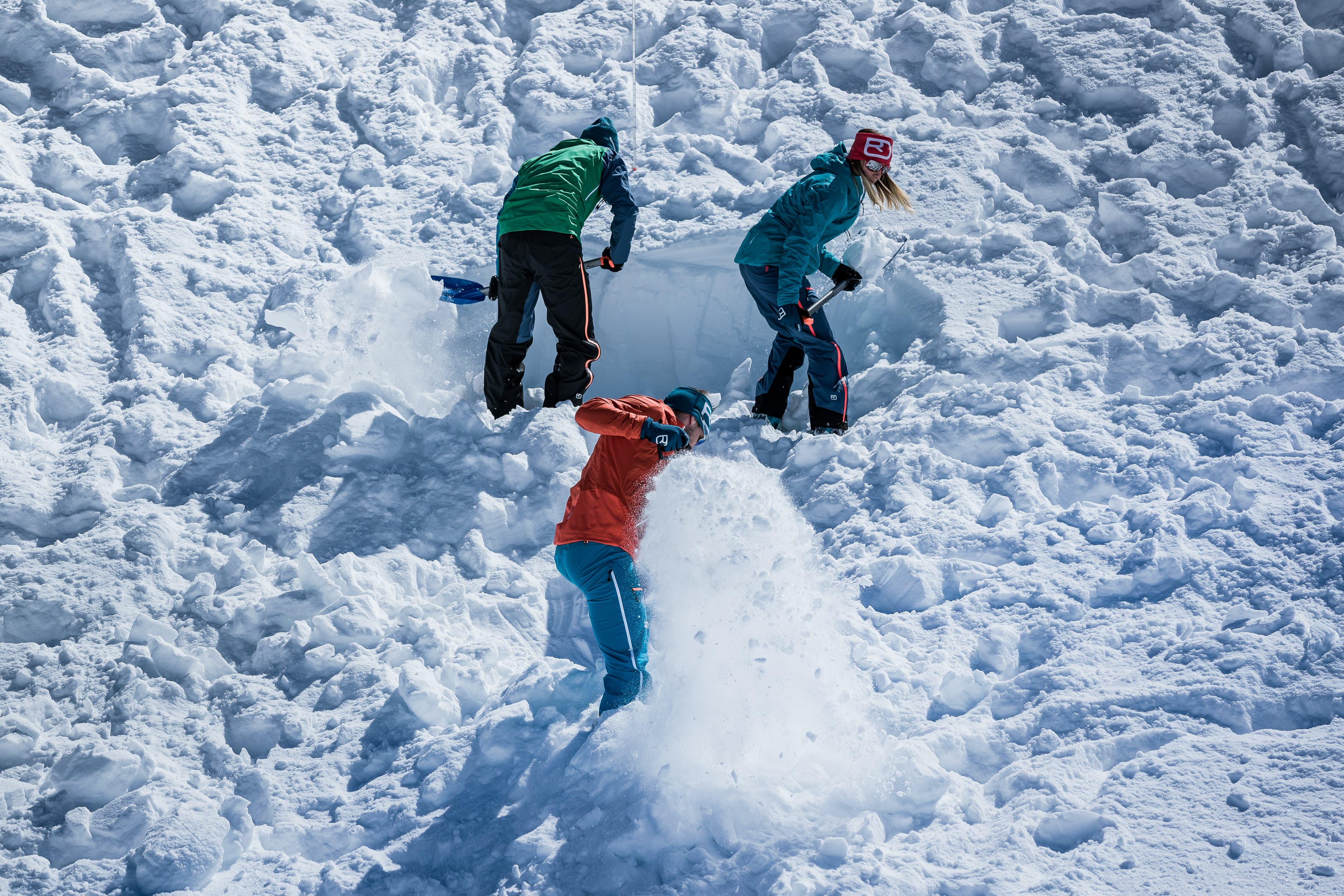 Backcountry skiers dig in snow to recover buried avalanche transceiver