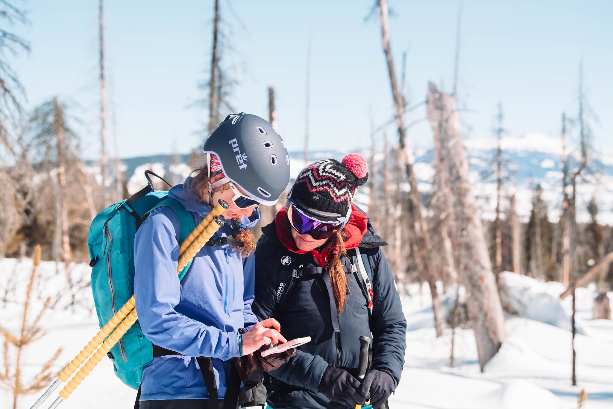 Two skiers looking at a phone.