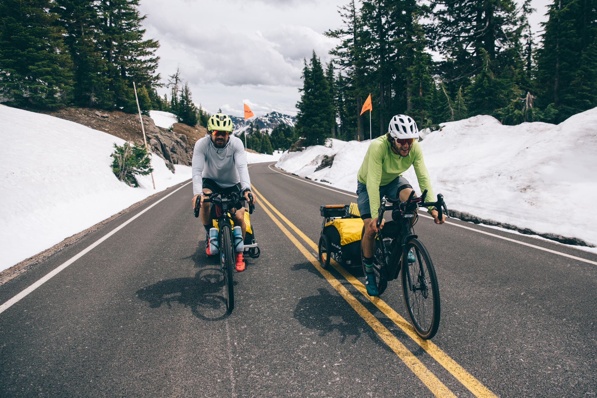 two people riding bikes with gear trailers
