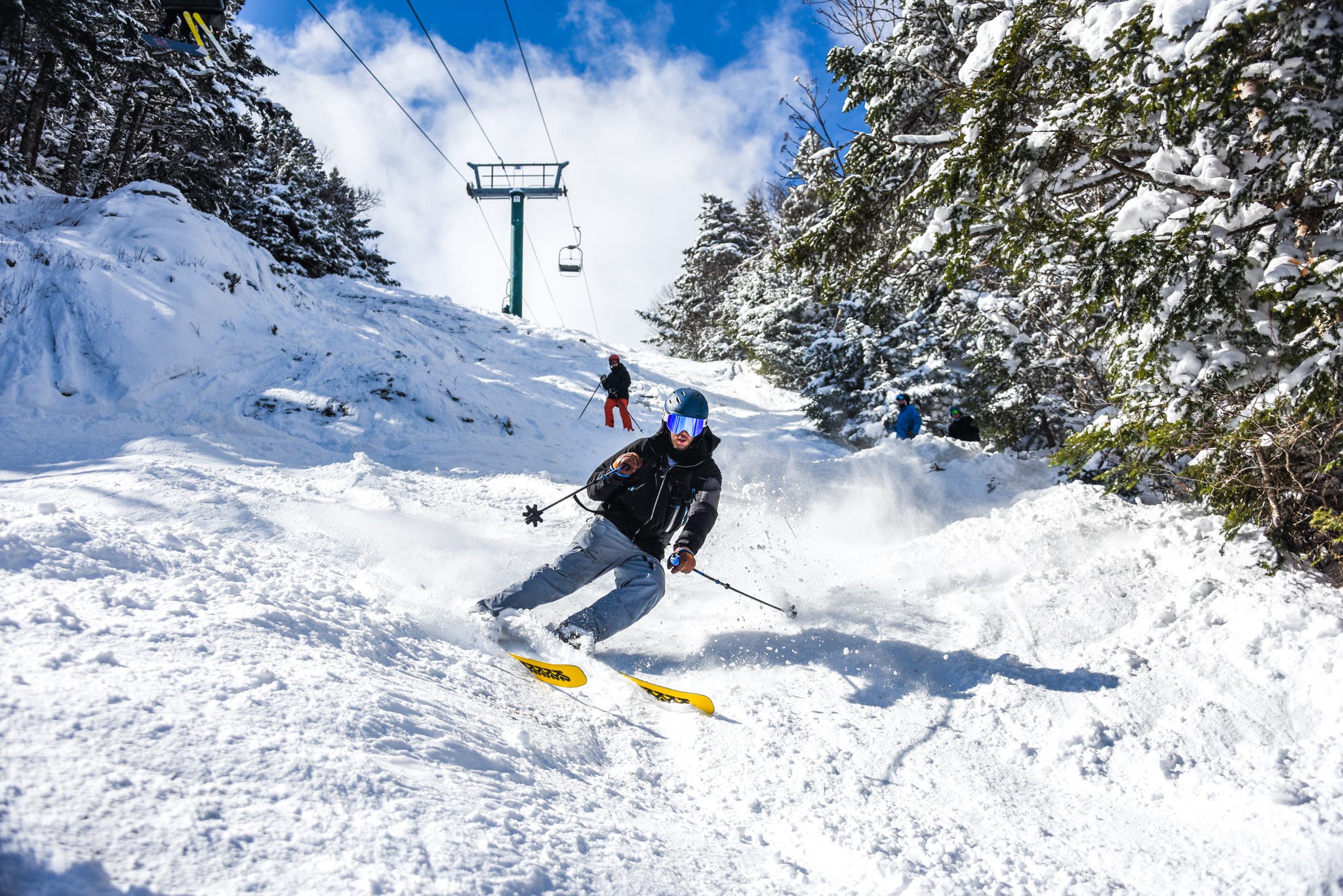 Skier races down the mountain on a bluebird day