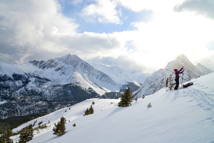 Skier adjusts skis at top of mountain.