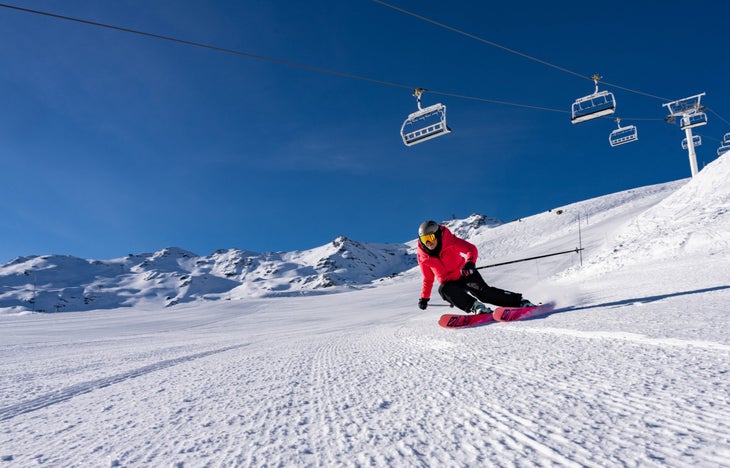 Skier in a red jacket against a bright blue sky.