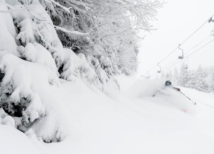 Skier zooming down with plenty of powder.