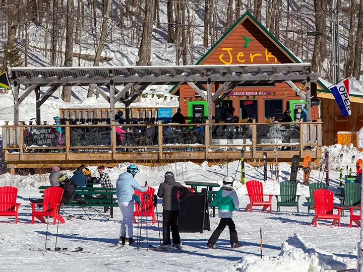 Small cabin with "jerk" painted out front and skiers outside.