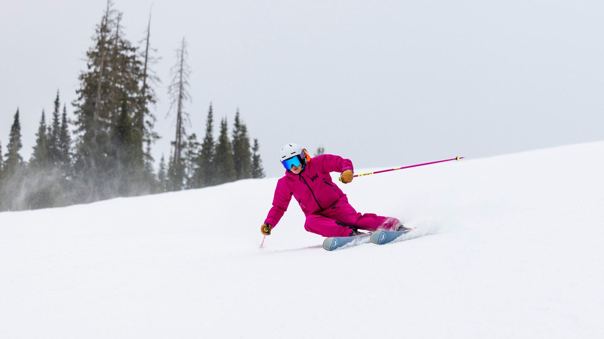 Woman in pink carving on Rossignol Rallybird Soul 102 wide all-mountain ski down groomed slope