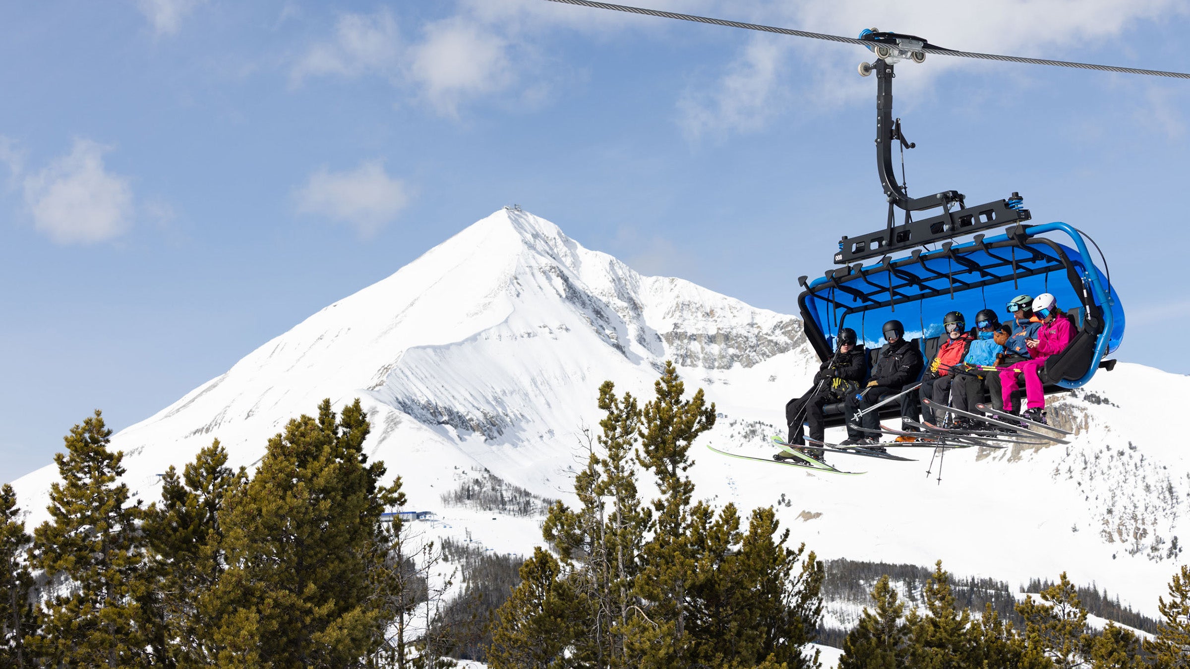 Skiers on 8-person chairlift at Big Sky Resort, Lone Peak in the background