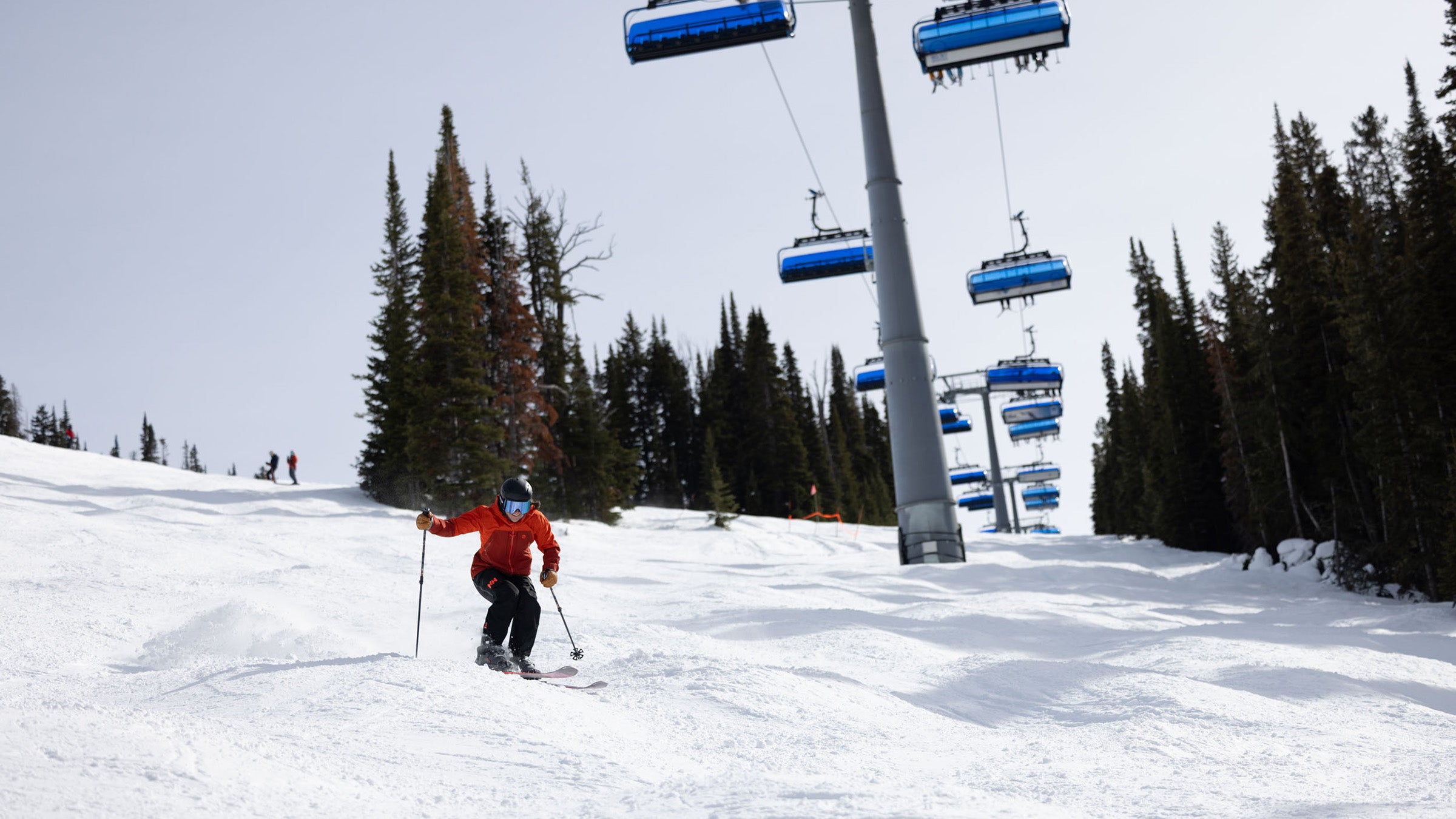 Skier in red jacket skiing moguls under chairlift