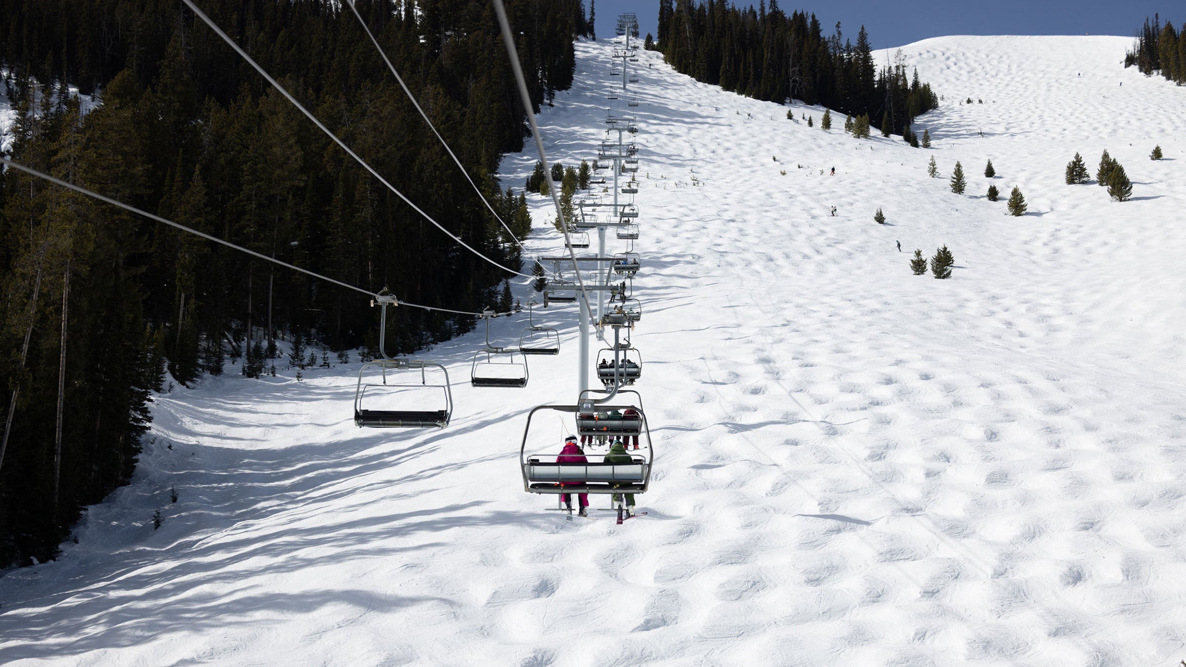 Skiers sitting on chairlift with mogul field in background