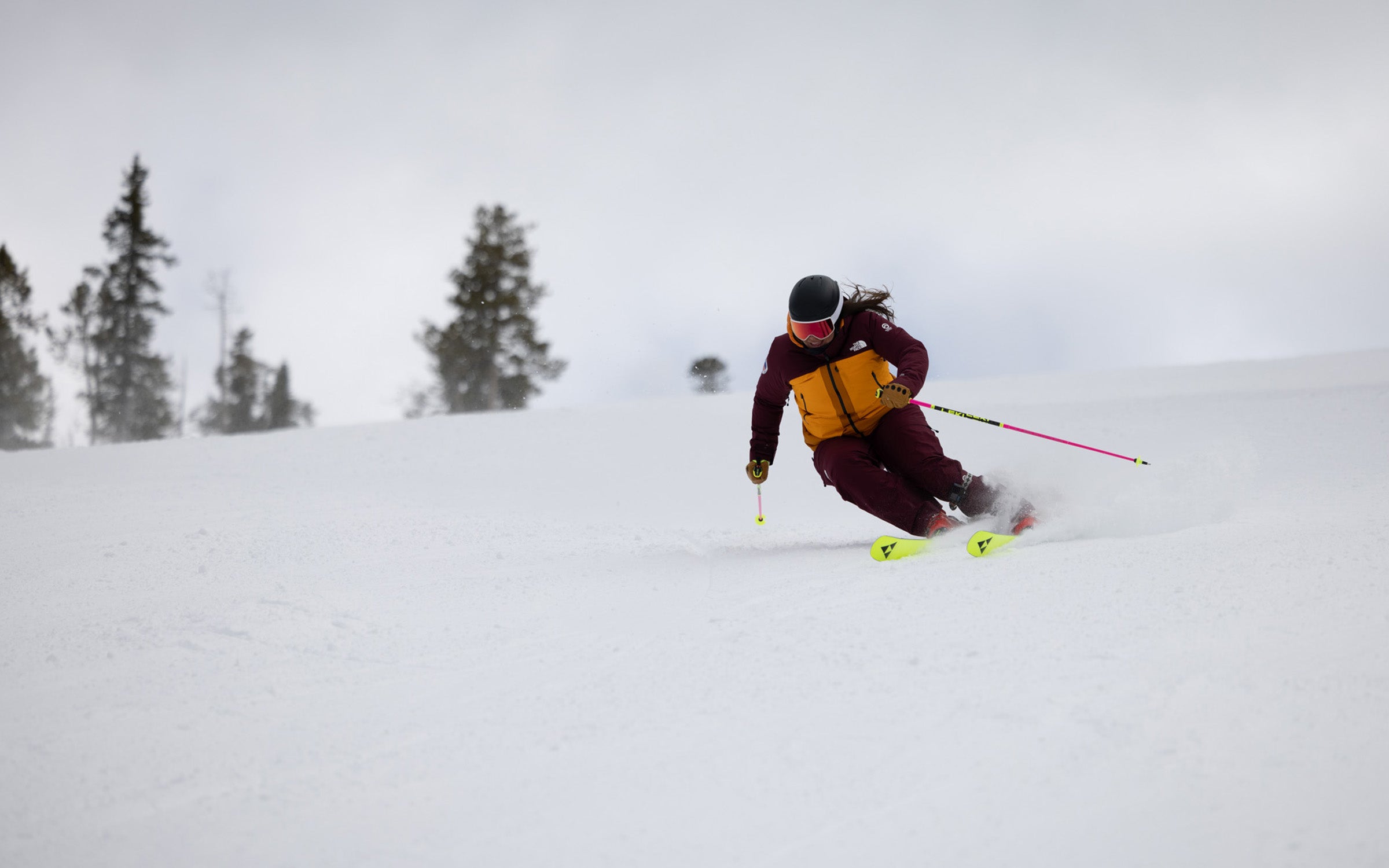Woman in red ski suit skiing down groomed slope