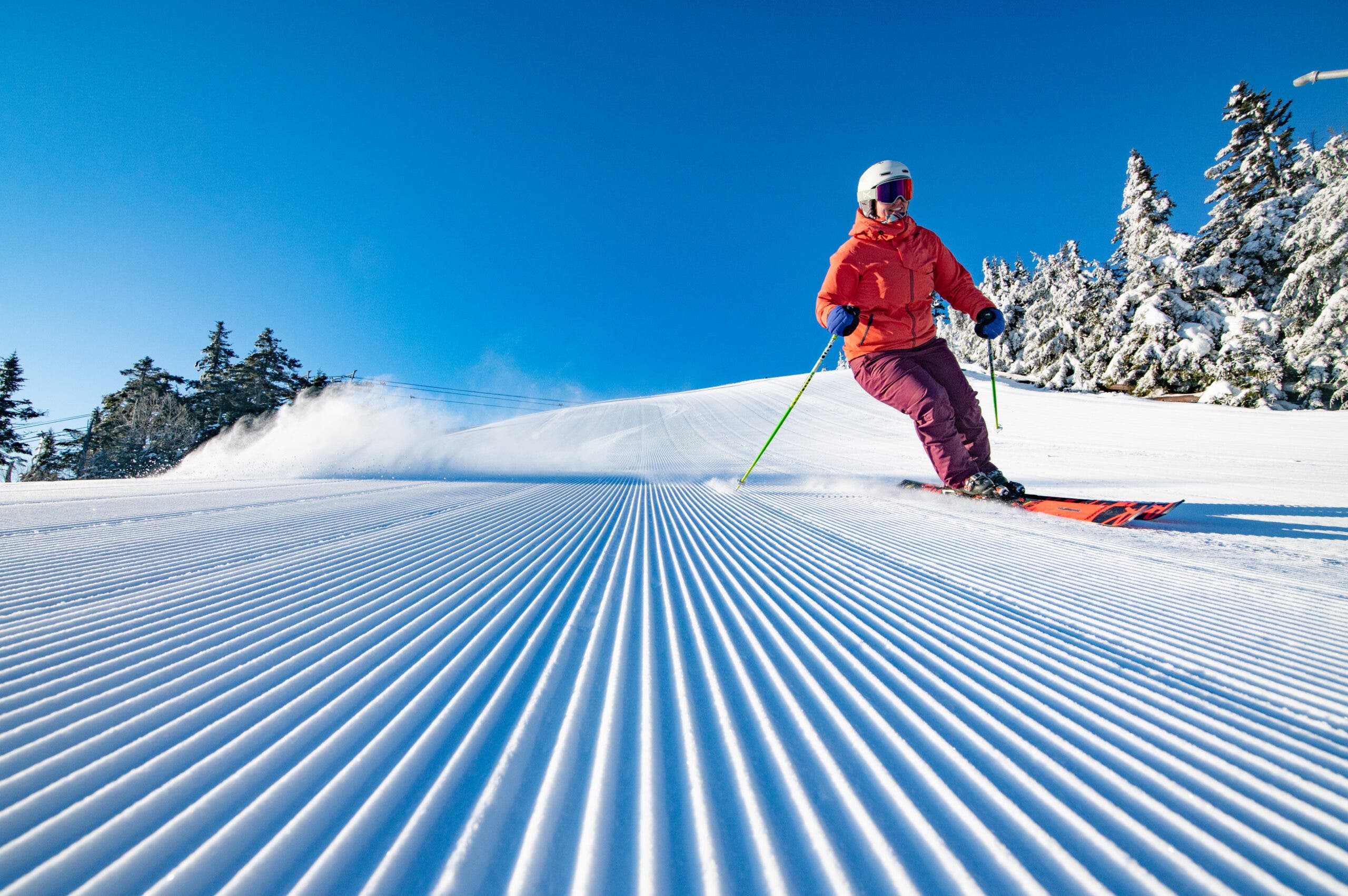 Pemain ski berjaket merah muda di groomer