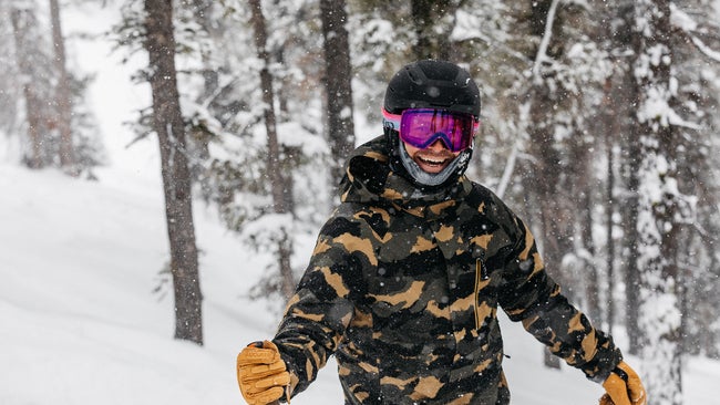skier wearing pink goggles smiling against snowy background