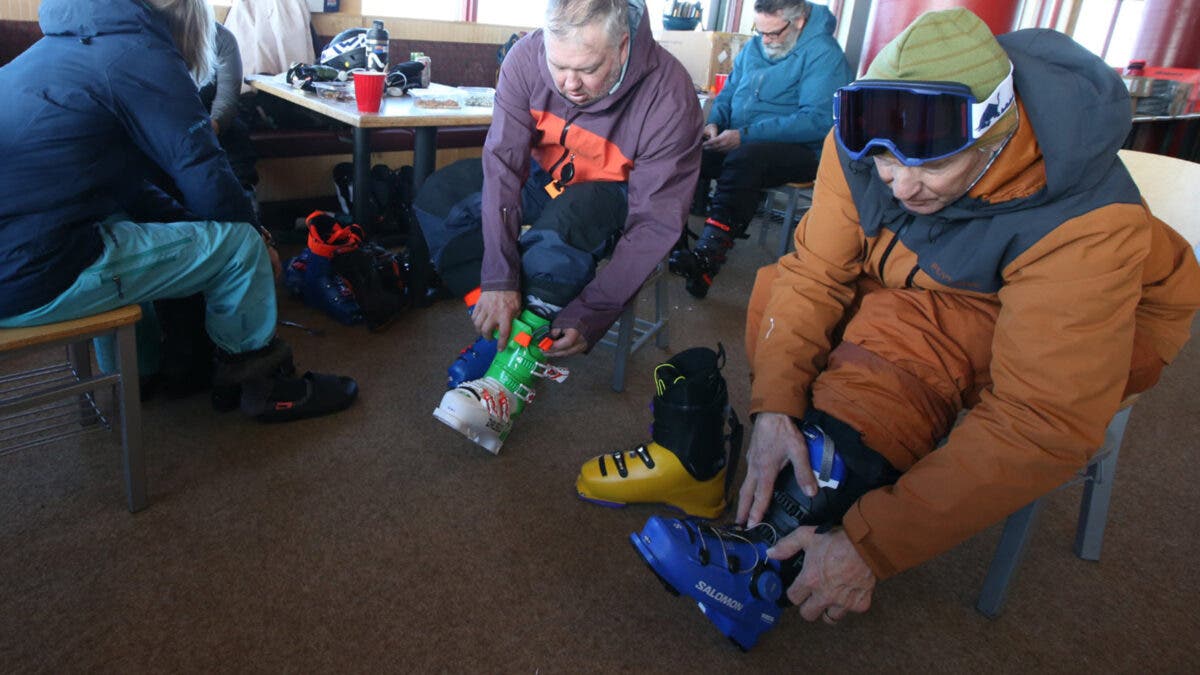 Men buckling up ski boots inside lodge at Masterfit ski boot test