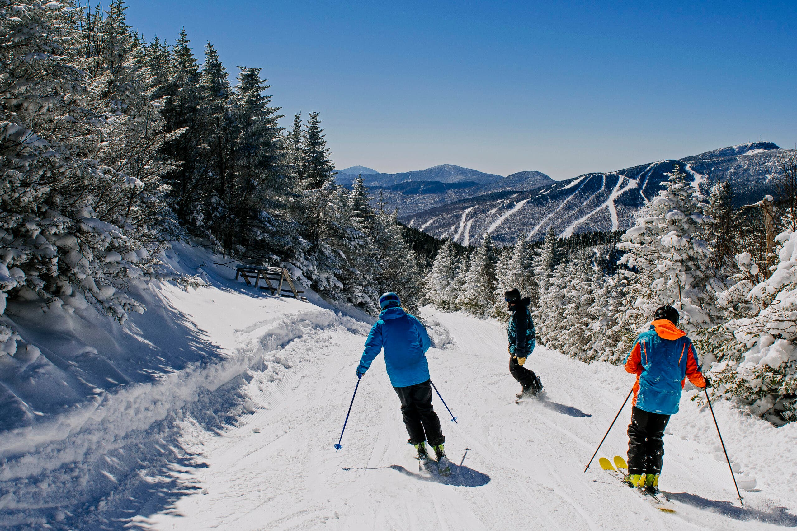 Tiga pemain ski sedang berlari