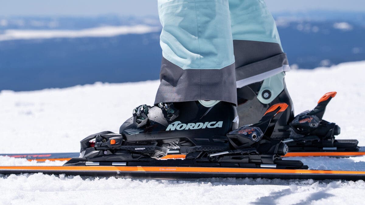 Closeup of black black Nordica women's ski boots clicked into skis on snow