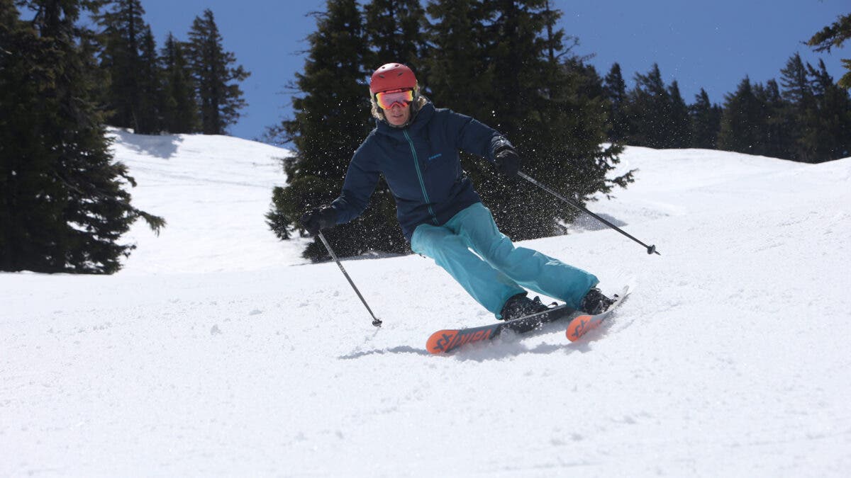 Woman in blue jacket and blue pants skiing on groomed run while testing the best women's ski boots 