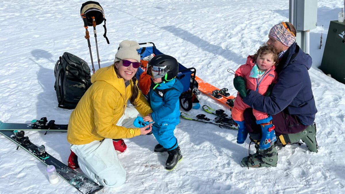 Family with young kids testing kids ski helmets on snow