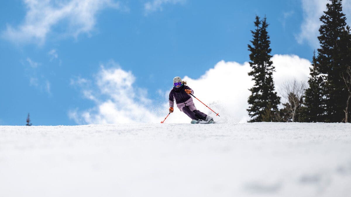 Woman skiing down snowy slope on sunny day on Rossignol Arcade carving skis.