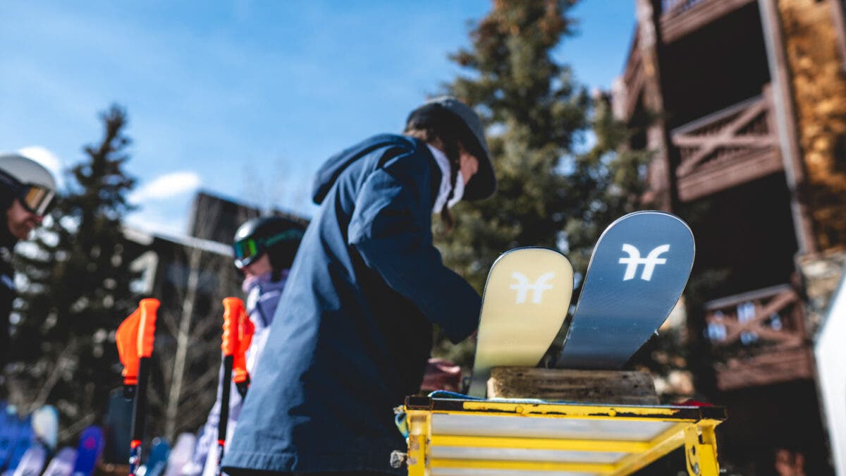 Woman bending over tips of Faction skis on ski tuning table