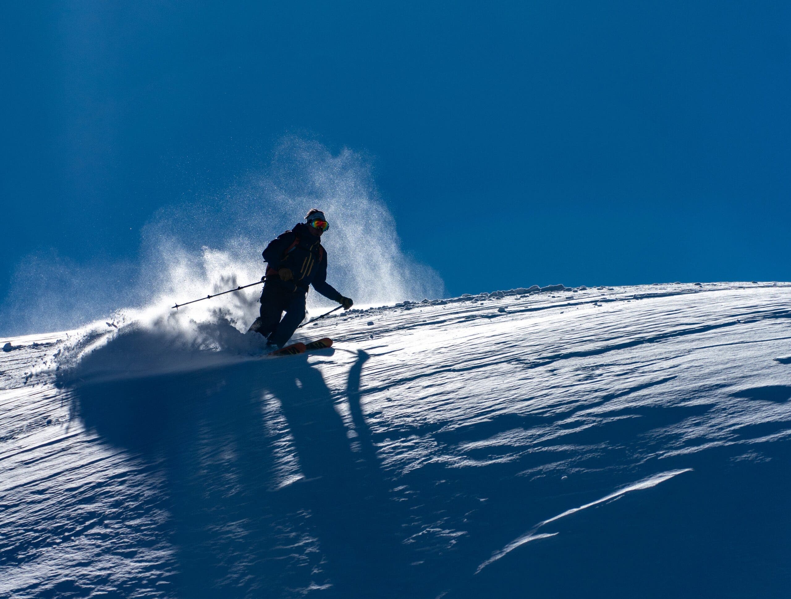 Skier illuminated by blue sky behind him.