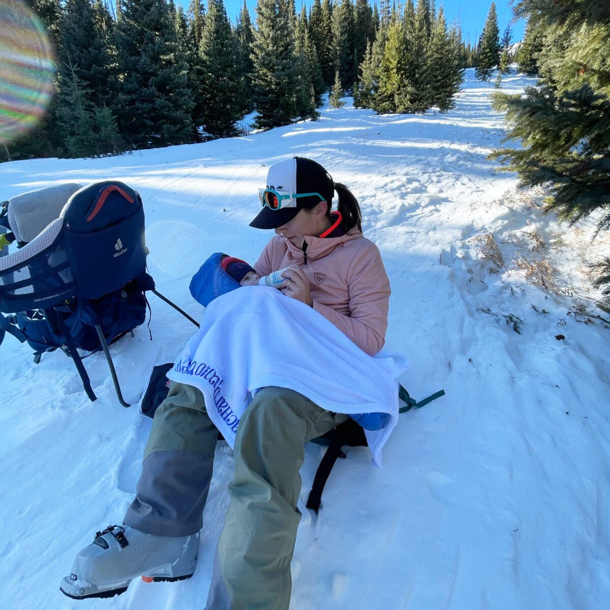 Mom skier feeding baby in the middle of a backcountry ski tour