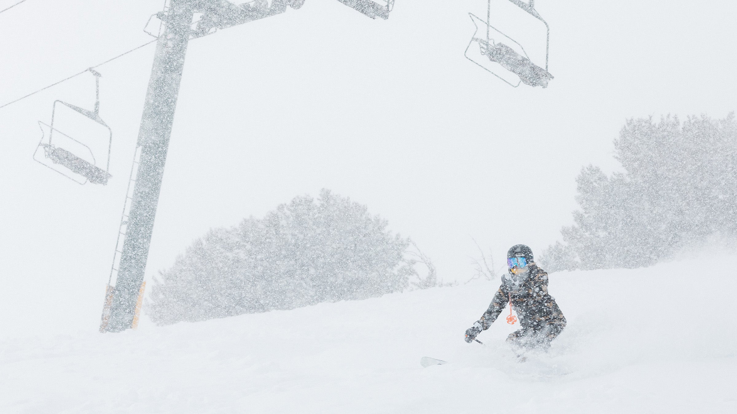 Skier skiing through snow storm with chairlifts in background